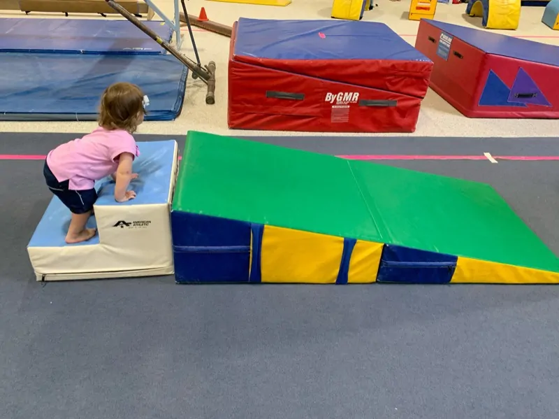 toddler on foam wedge at gymnastics 