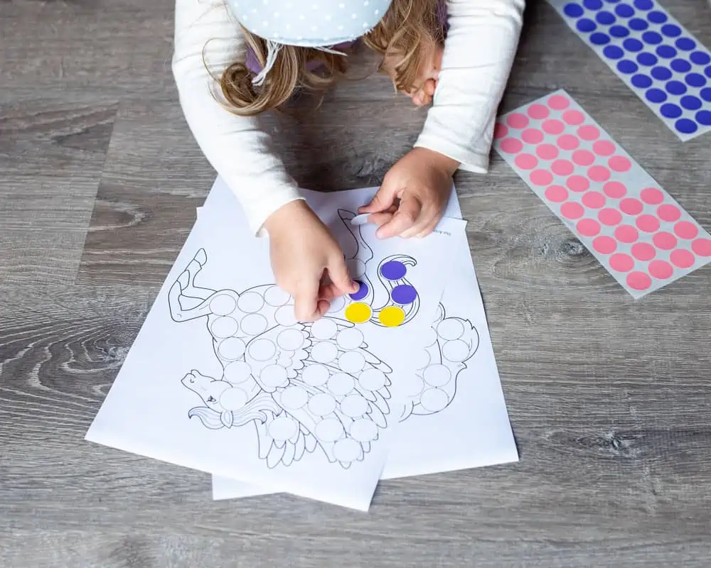 A child planning a purple round sticker on a Pegasus dot marker coloring pages
