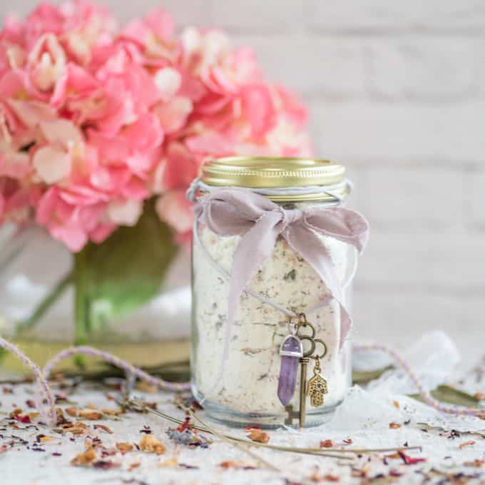 a jar with powdered goat milk bath soak. The jar is tied with a purple ribbon.