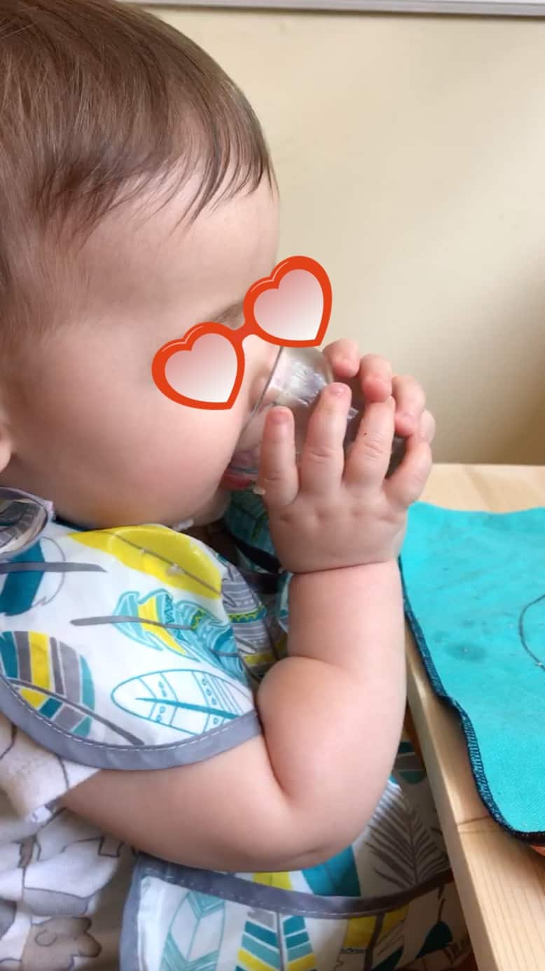 Montessori baby using a tiny glass