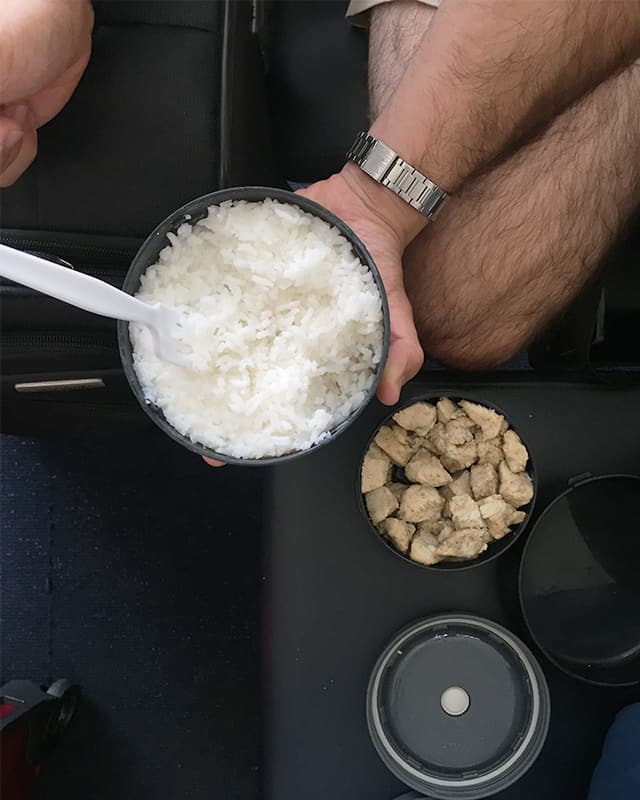 enjoying a hot meal of chicken and rice at the airport