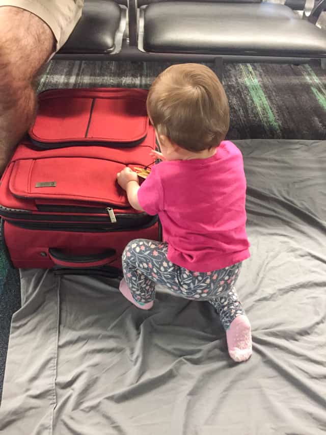 baby playing on airport floor on a bedsheet