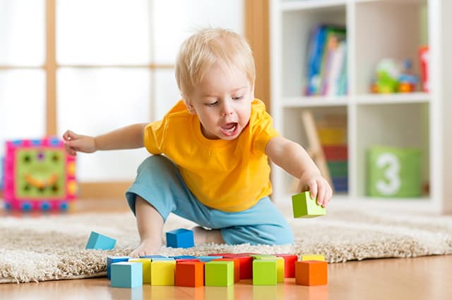 a toddler playing with wood blocks