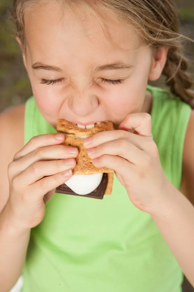 Child eating smore snack on camping trip