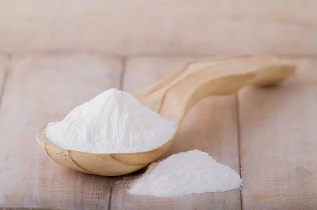 a spoon full of baking soda on a wood background