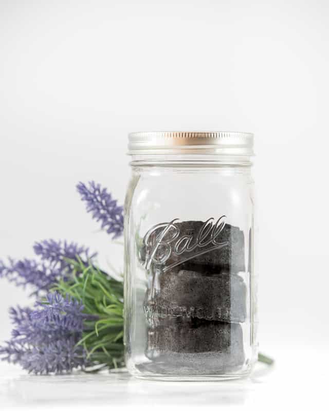 three black bath bombs with activated charcoal in a mason jar