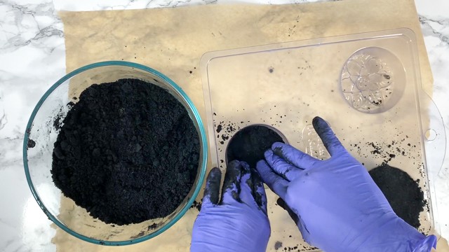Packing black bath bomb mixture into molds