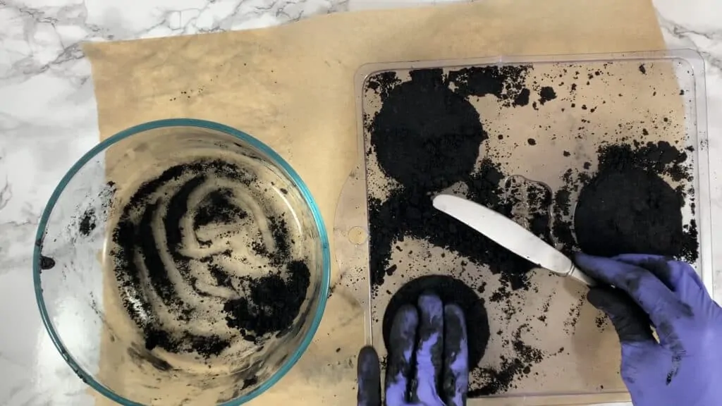 Scraping bath bomb molds with a knife to remove excess mixture