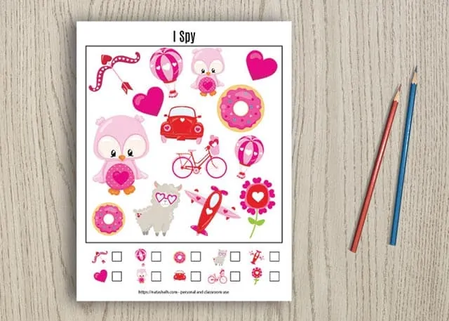 Free printable Valentine's Day I spy game for young children on a wood background with two pencils