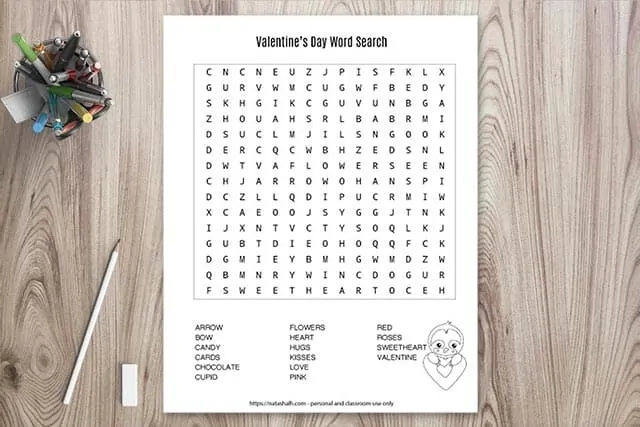 Printable Valentine's Day word search on a wood background with a cup of pens and a pencil