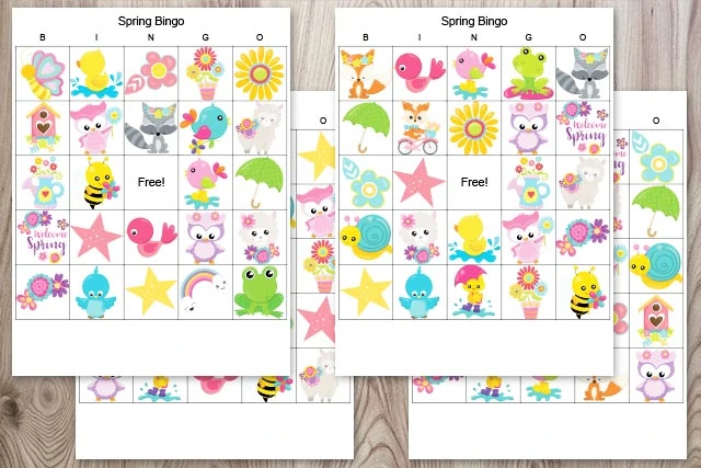 four free printable picture bingo cards for spring on a wood background. The bingo cards feature cartoon images like foxes, birds, frogs, and flowers