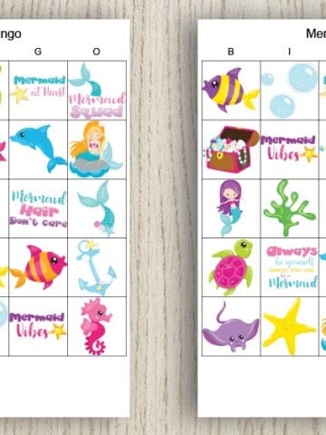 two free printable mermaid bingo cards on a wood background. The cards feature brightly colored mermaid and undersea themed images