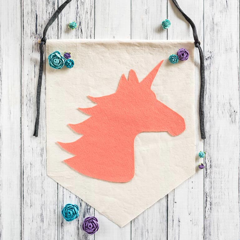no-sew felt unicorn banner on a white background with paper flowers. 