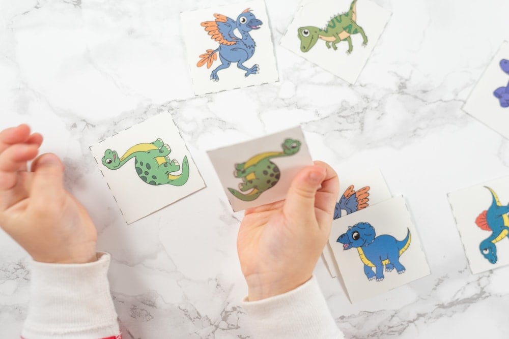 Toddler playing with dinosaur matching card printable game