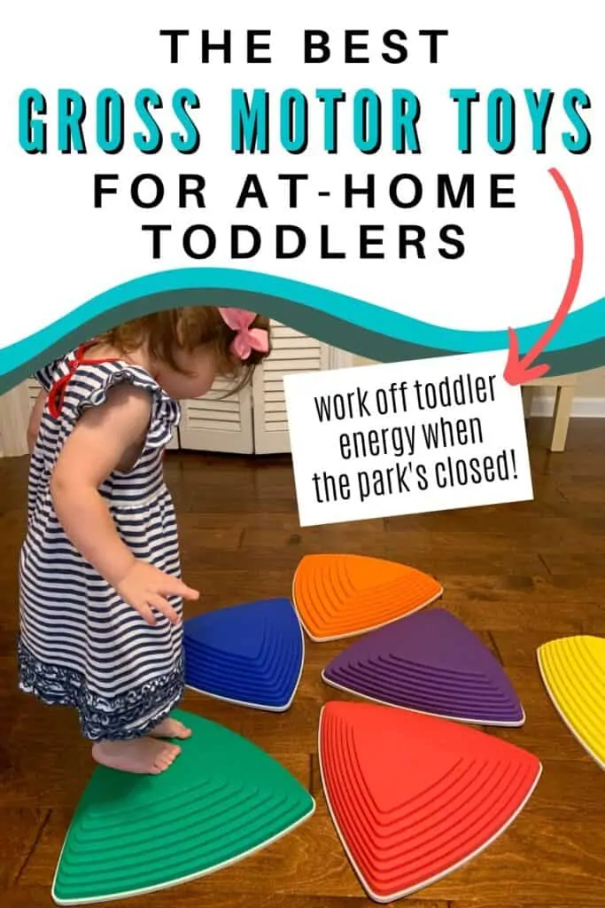 Text "the best gross motor toys for at-home toddlers" There is an arrow pointing at additional text "work off toddler energy when the park's closed!" Below the text is a picture of a young toddler in a blue and white striped dress using plastic stepping stones on a wood floor.