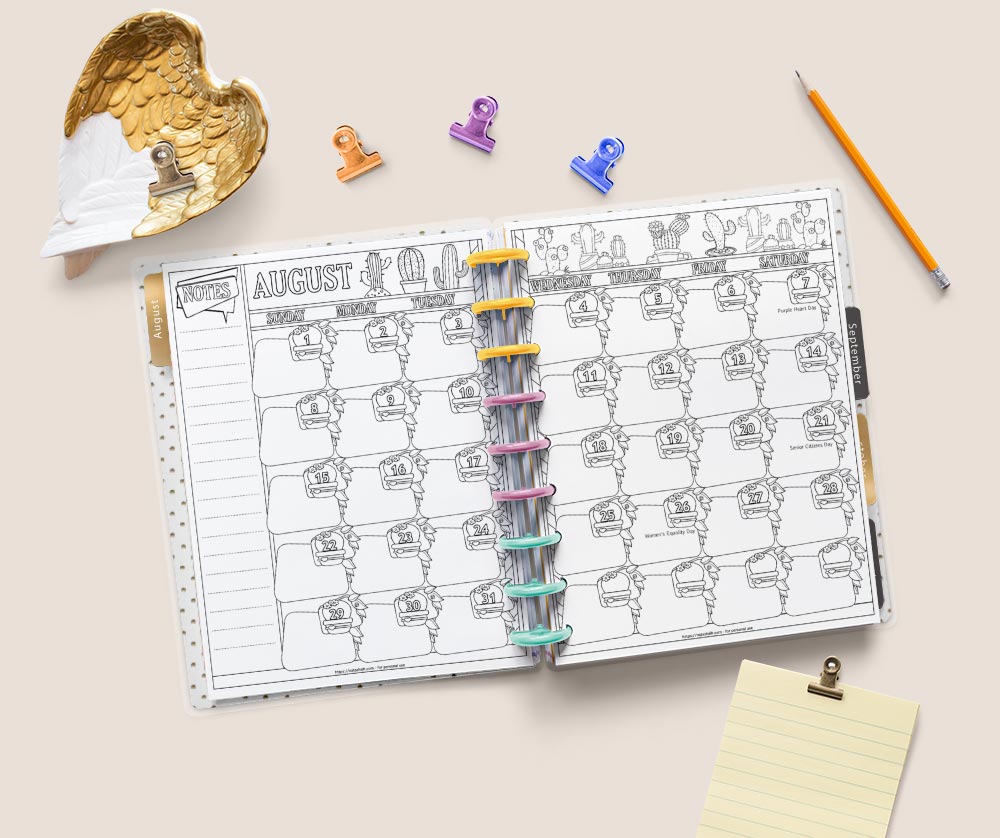 A flatly image of a Happy Planner Classic open to a double page spread for the month of August 2021. The pages have cacti to color. Around the planner are desk supplies including a yellow pad of paper, a tray shaped like feathered wings, four binder clips, and a yellow pencil.