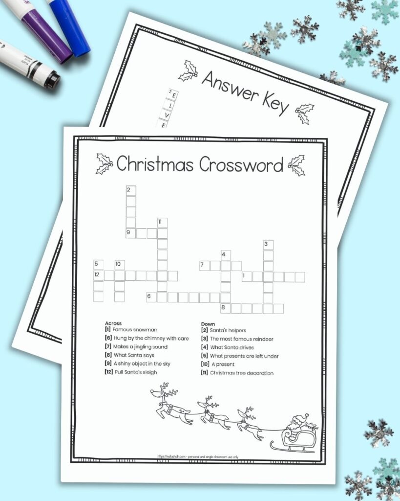 A free printable Christmas crossword puzzle for children with a doodle frame border and black and white image of Santa with his sleigh. The crossword is on a blue background surrounded by children's markers and snowflake shaped confetti. Behind the page with a crossword puzzle a second page is barely visible. It is the puzzle's answer key.