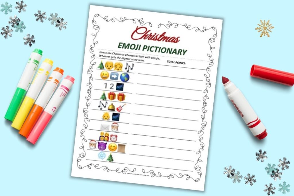 A flatly of a printable Christmas emoji Pictionary printable game on a teal background. The game has 10 Christmas phrases written in emojis to decode and solve. There are colorful children's markers and snowflake shaped confetti on the blue surface.