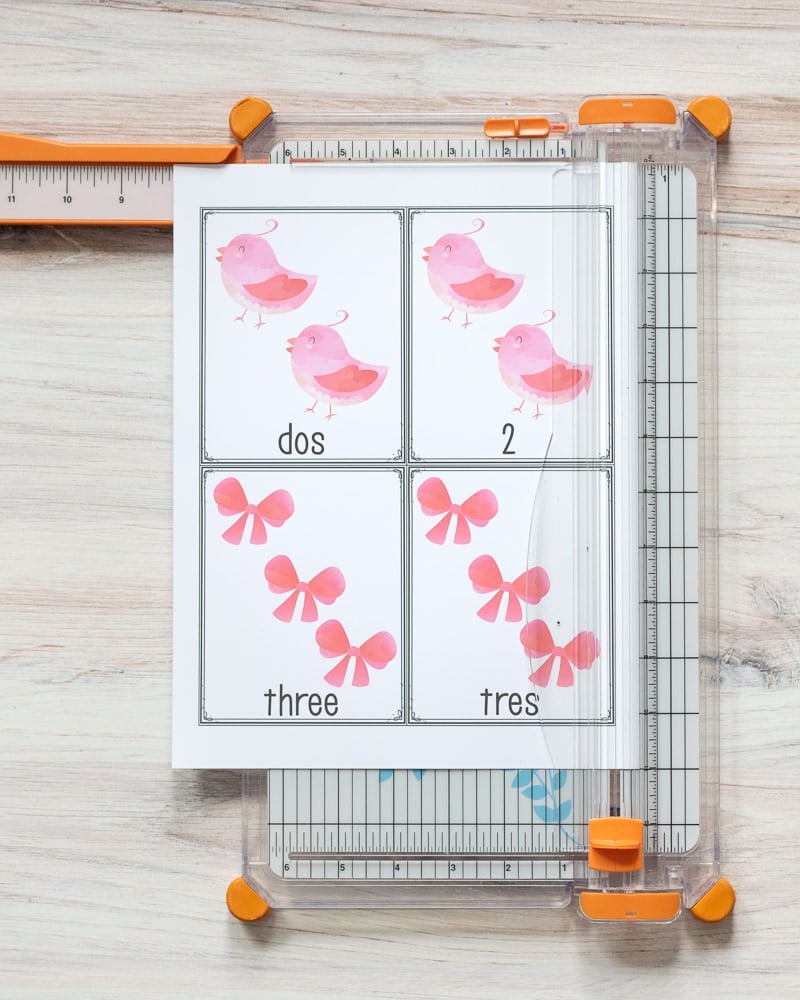 A printed page of Valentine's Day counting cards with birds and bows. The page is sitting on a paper trimmer ready to be cut into four separate cards. 