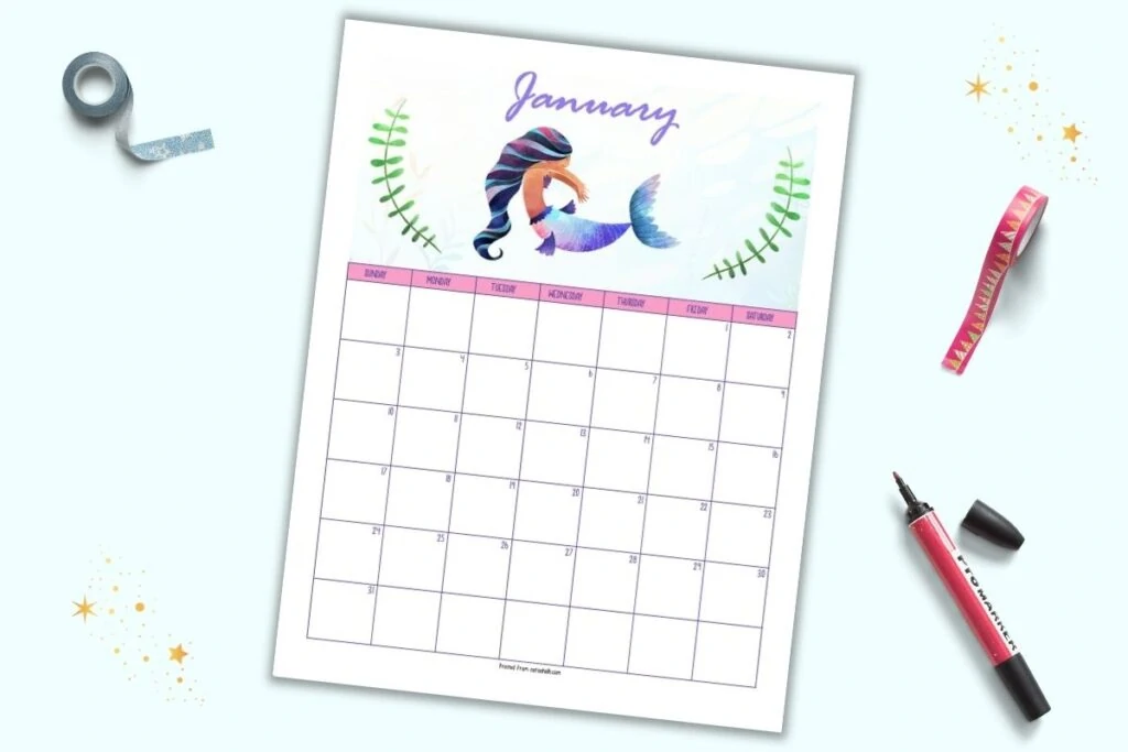 A printable January 2021 calendar page with a mermaid theme. The mermaid at the top has a purple and pink fin and is centered between two pieces of green seaweed. "January" is in script at the top. The page is shown on a blue background with a red marker and rolls of washi tape. 