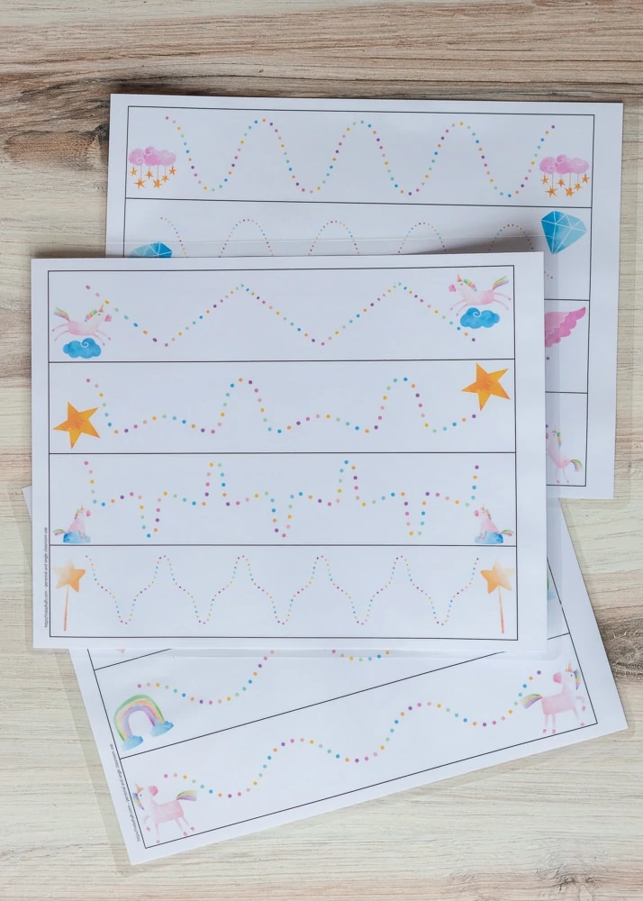 Three printed pages of preschool tracing pages with a unicorn theme. Each page has four rectangles. A line of rainbow dots is in each rentable and a unicorn-themed image is on each end of the dotted line. 