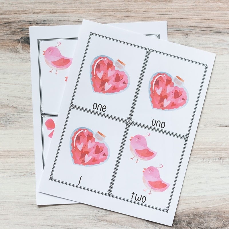 A picture of two printed pages with four cards each to a page. The top page has three cards with 1 bottle of hearts and one card with two pink birds. Th cards are labeled "one, uno, 1, two"