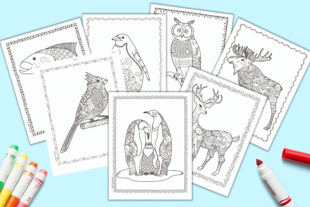 A flatlay preview of 7 printable winter coloring pages for adults. Each page has a winter animal willed with doodles to color. The border of each page has a hand drawn doodle frame. The coloring pages feature a family of penguins, a deer, a moose, an owl, a lone penguin, a cardinal, and a salmon.