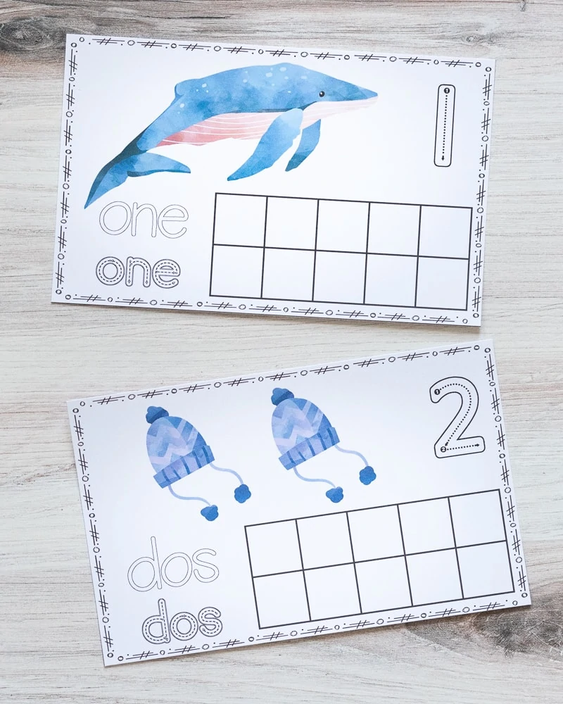 Two printed ten frames with a winter theme. The top one has a single whale and "one" written in bubble letters and in correct letter formation graphics. The lower card has "dos" to demonstrate that the winter ten frame printables are available in both spanish and English