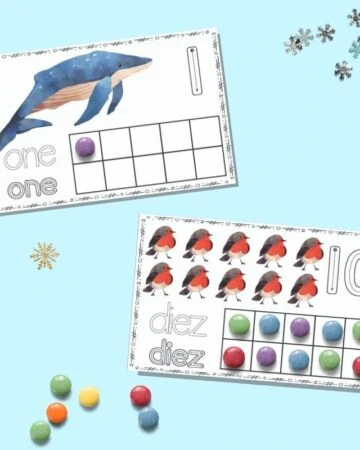 Two printable winter ten frame cards on a blue background. The upper card has "one" and a single whale with a purple candy in the first spot on the ten frame. The lower card has "diez" with ten red robins and all squares on the ten frame filled in.