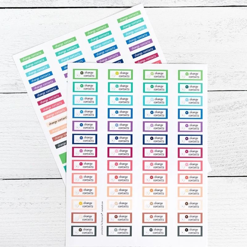 Two printed pages of printable planner stickers. The stickers say "change contacts" in a variety of rainbow colored boxes. They are shown on a white wood background.