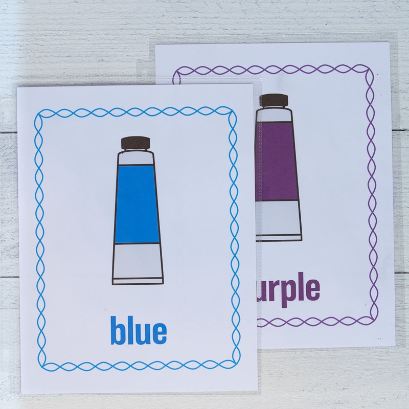 Two printed color posters in page protectors on a white wood surface. The colors are blue and purple. 