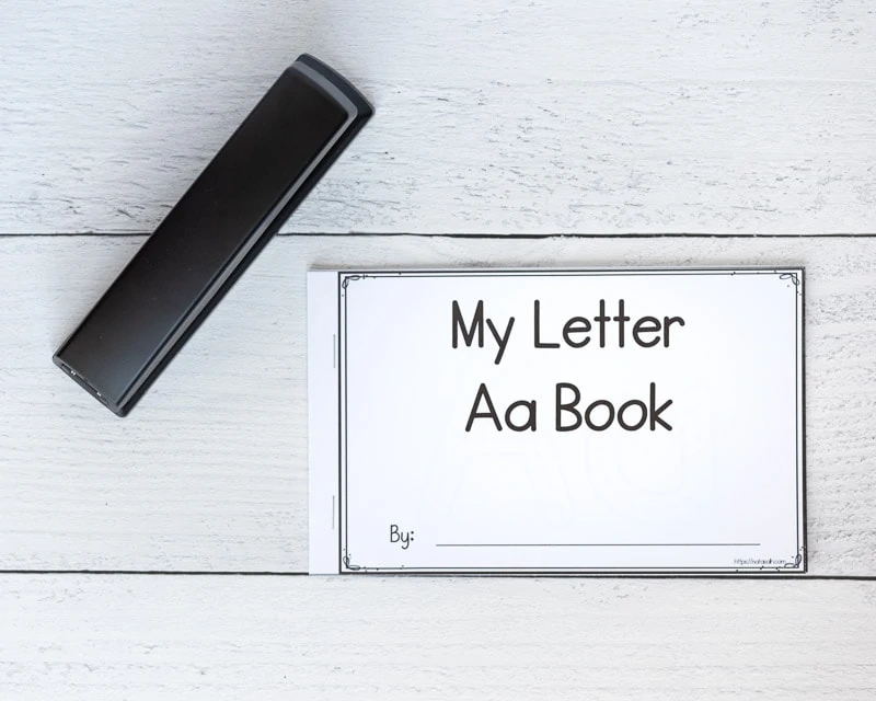 A printed letter a emergent reader next to a black stapler