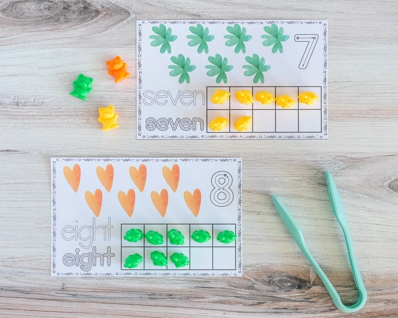 A top down picture of two printable ten frame cards. One has seven shamrocks and the other has eight hearts. Both have the appropriate umber of squares filled in with counting bears. 