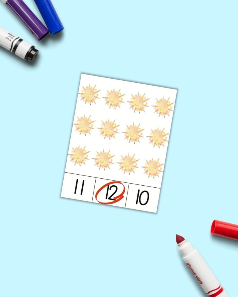 A free printable count and clip card with 12 smiling suns. At the bottom of the three cards are three numbers - 11, 12, 10. The 12 is circled in red. 