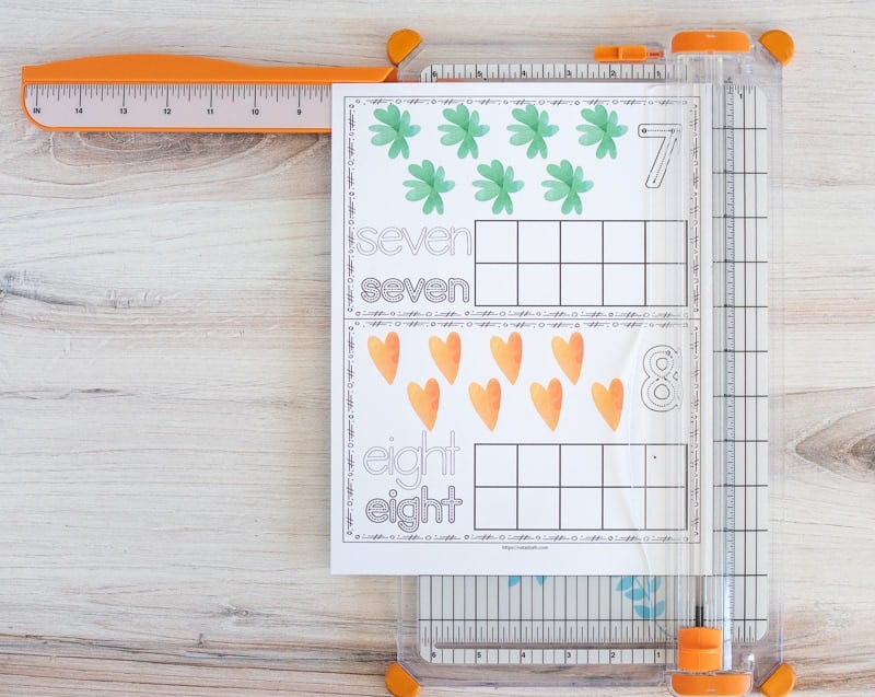 A page with two ten frame printables on a paper cutter. The ten frames have seven shamrocks and eight gold hearts. 