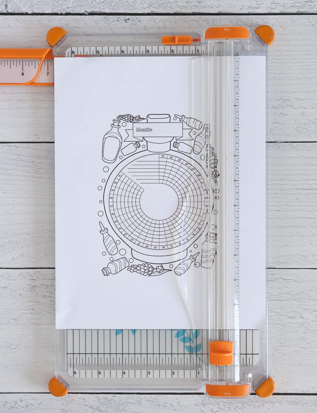 A photo of a lavender themed black and white coloring page habit tracker on a paper trimmer.