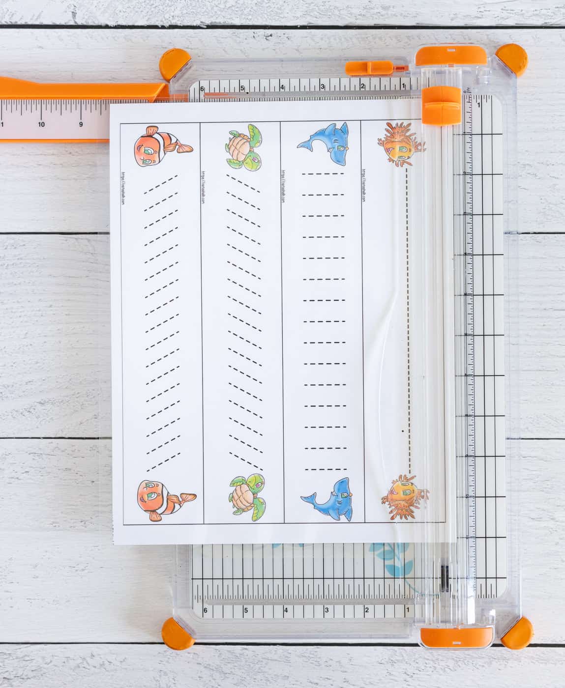 A page of laminated prewriting practice cards being cut on a paper trimmer.