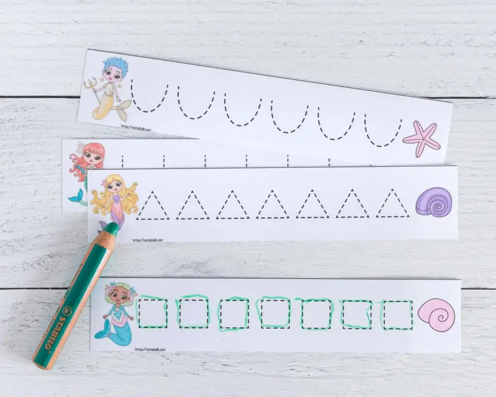 A preview of four cut apart and laminated prewriting practice cards with a mermaid theme. A card with dotted squares to trace has been traced with a green dry erase crayon.