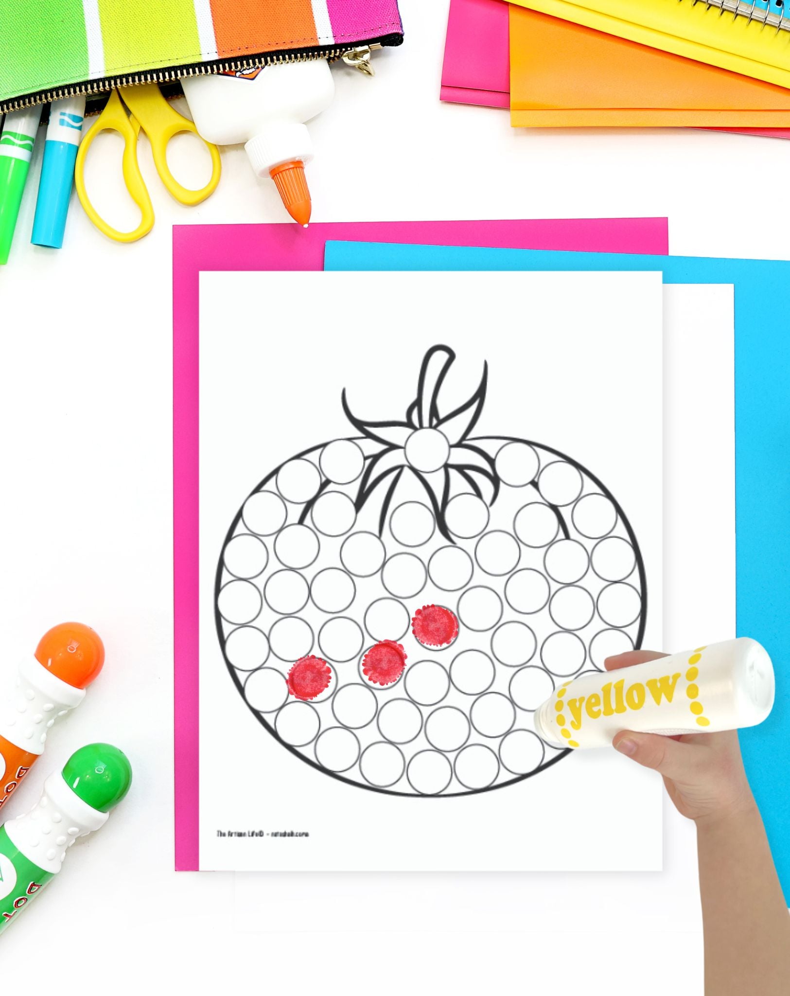 a child's hadn't with a dot marker preparing to color a tomato themed dot marker coloring page