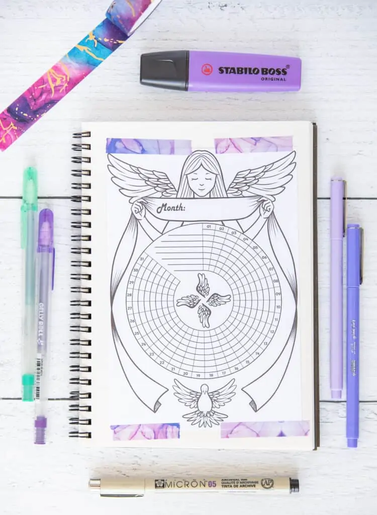 A printed angel themed habit tracker taped to a small spiral notebook with purple marbled washi tape.