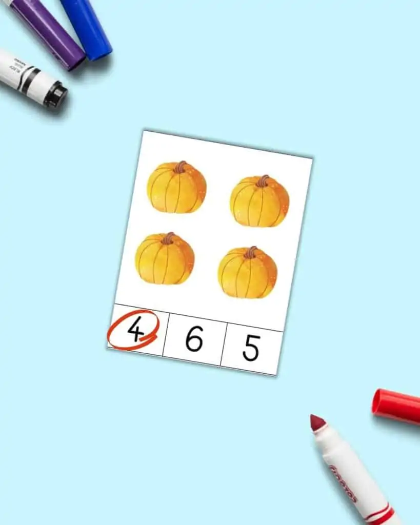 A pumpkin themed count and clip card with four pumpkins. Below are three numbers 4, 6, and 5. The 4 is circled in red.