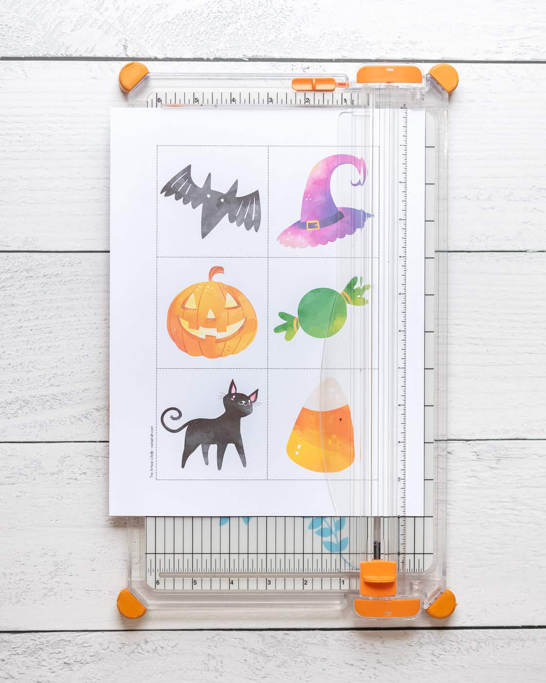 A page with six squares with dotted edges. The page is on a paper trimmer to cut the squares out along the lines.