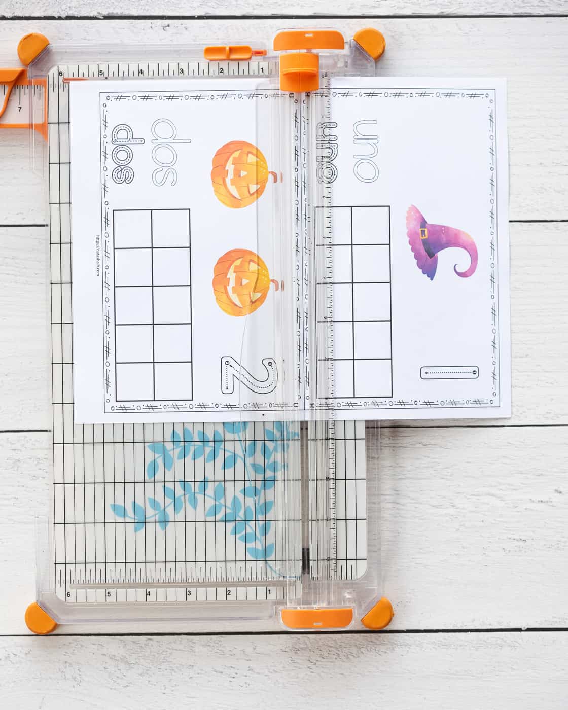 A page with two ten frame printables on a paper trimmer. The pages have 1 purple witch hat and 2 jack o lanterns, respectively, with a blank ten frame.