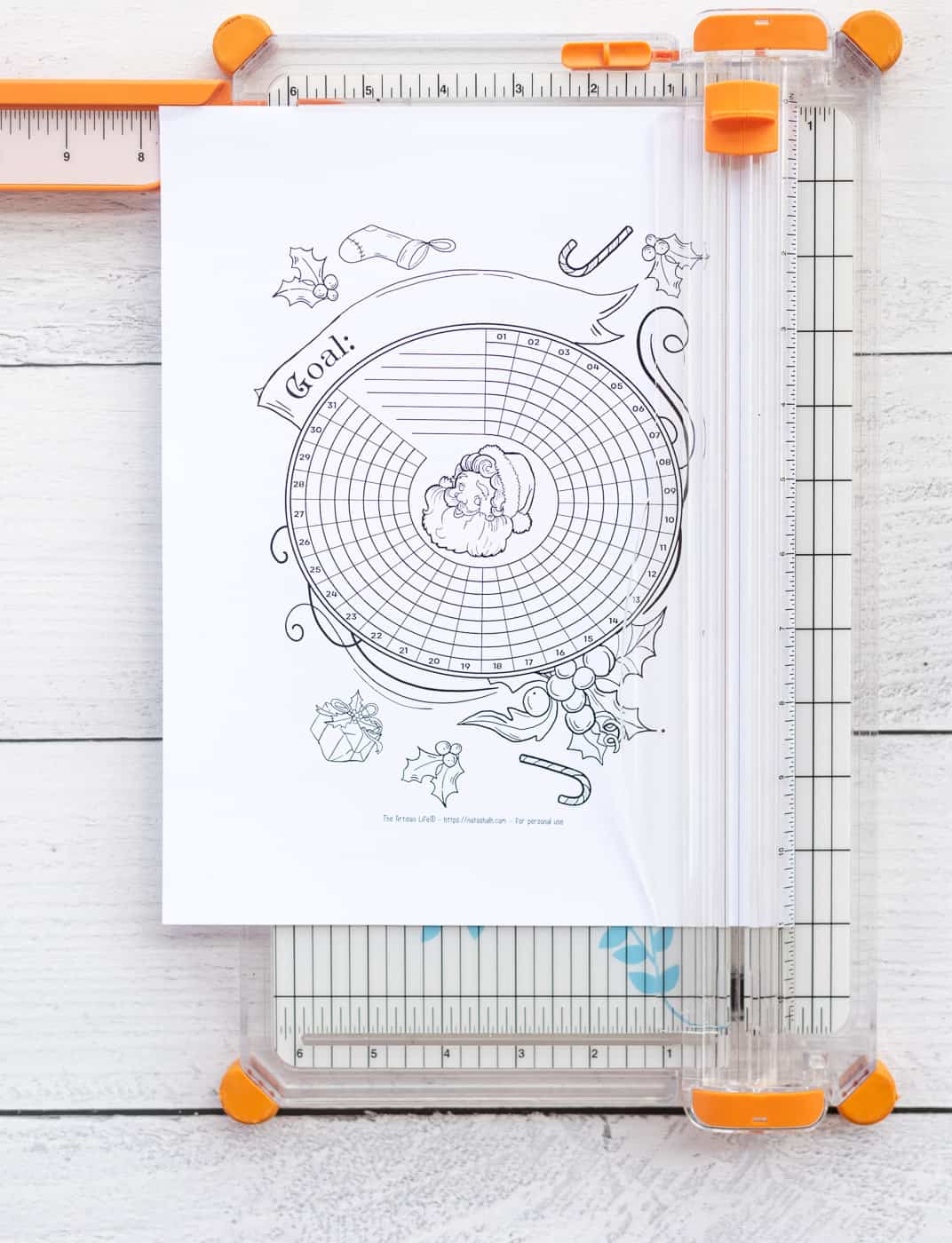 A printed Santa habit tracker on a paper trimmer ready to be cut down to Happy Planner size.