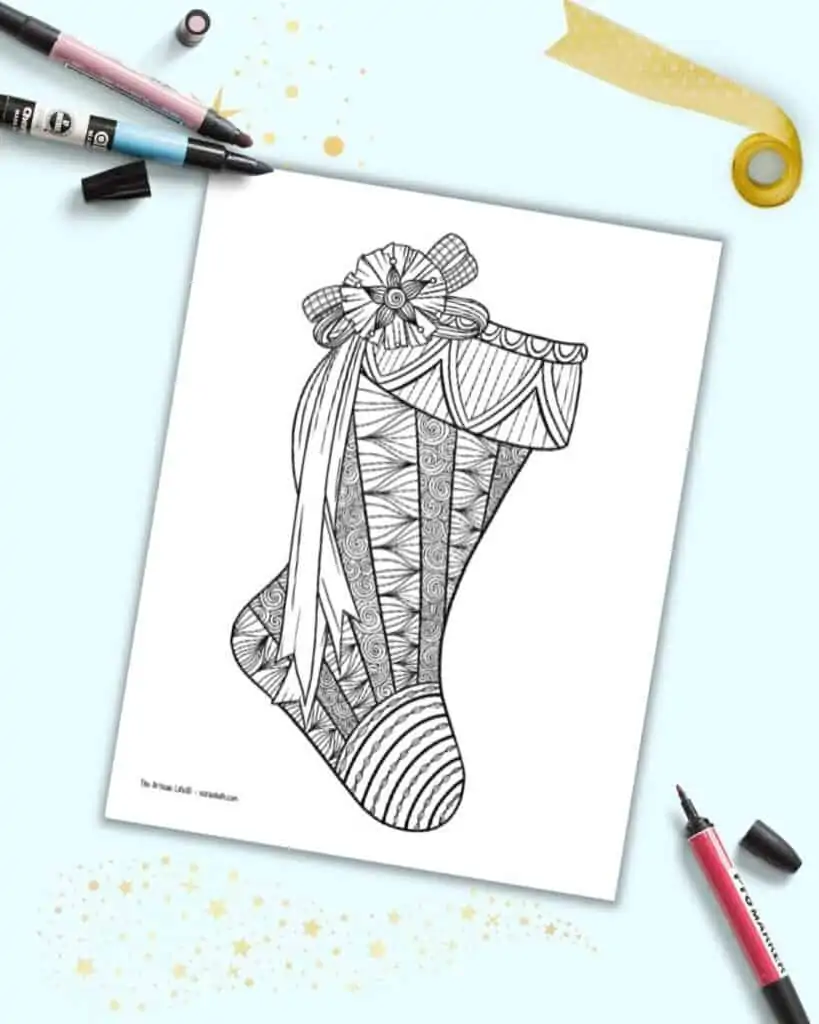 A preview showing a zen-style Christmas stocking coloring page for adults. The page is on a light blue background with three colorful markers.