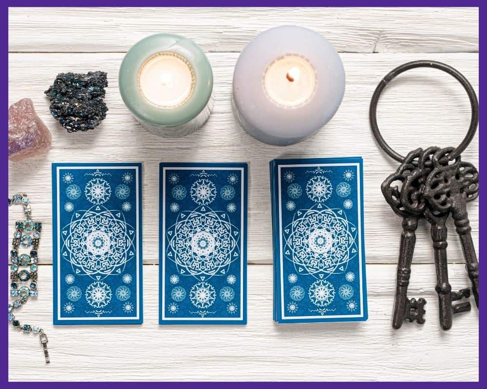 Three face down blue backed tarot cards on a a white wood table with candles and crystals