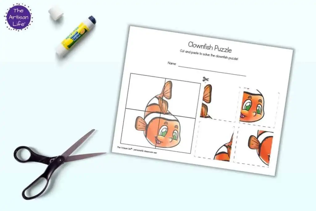 A preview of a printable four part puzzle with a clownfish. It is shown with a glue stick and a pair of scissors.