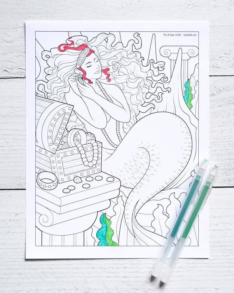 A partially colored mermaid coloring sheet with two green gel pens