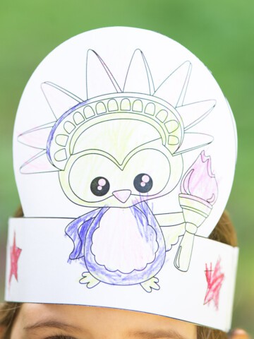 A child wearing a printable Fourth of July headband craft showing an owl as the Statue of Liberty