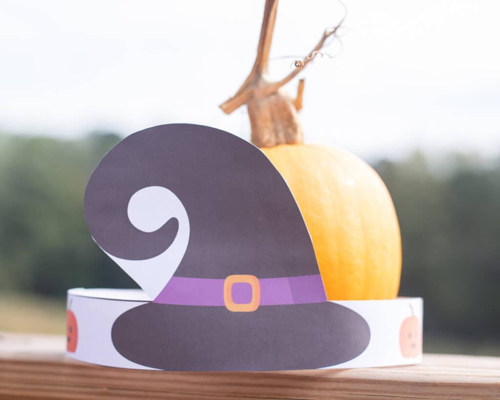 A witch hat headband around a small pumpkin